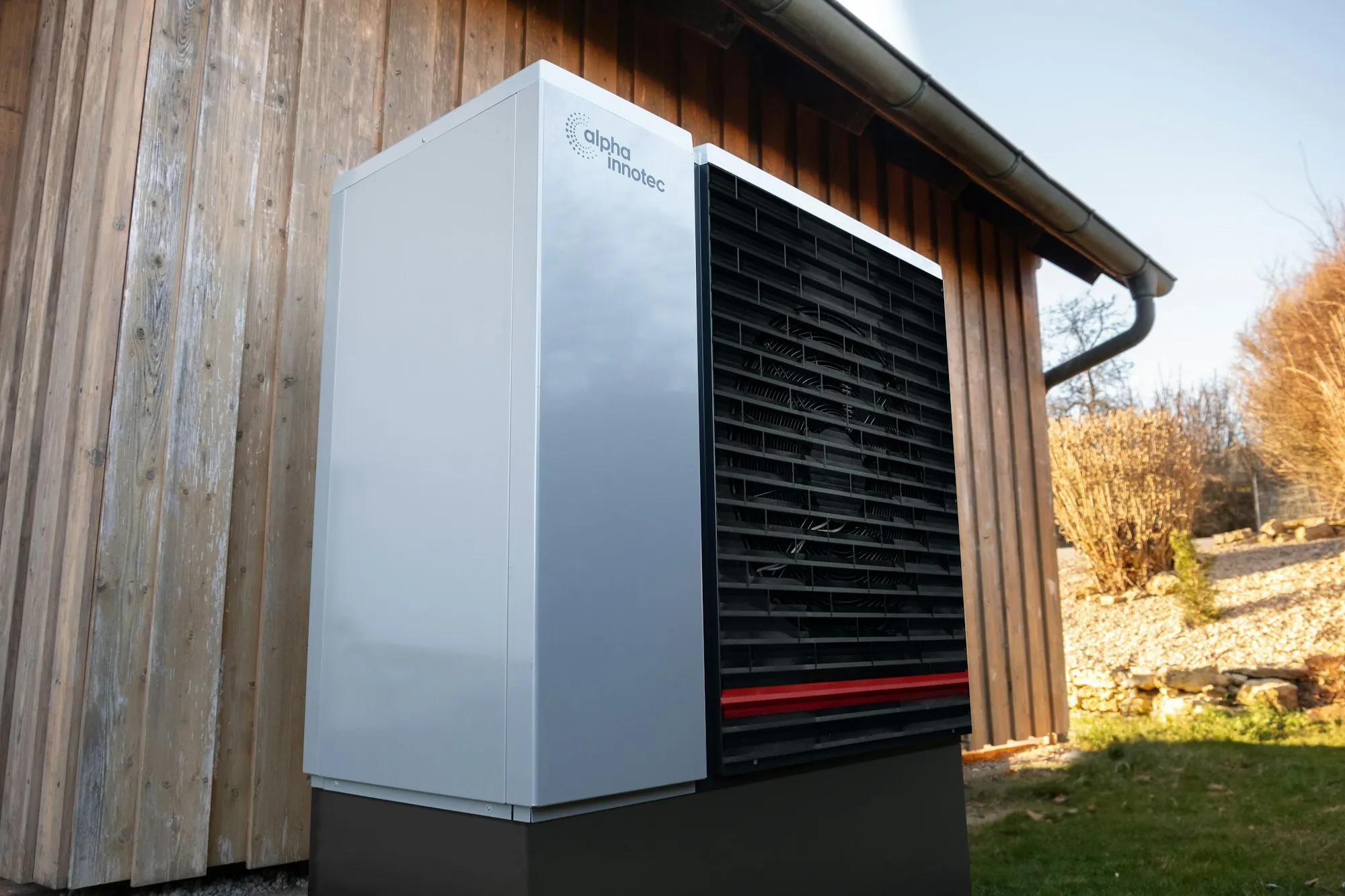 Tall heat pump unit beside a wooden shed wall